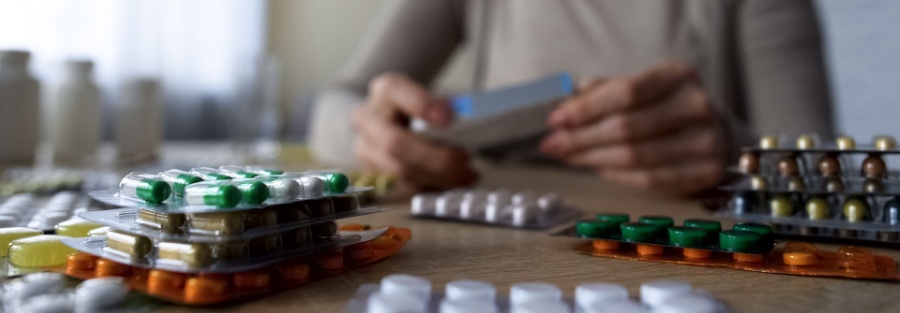 Persona revisando sus medicamentos para tomarse alguno.